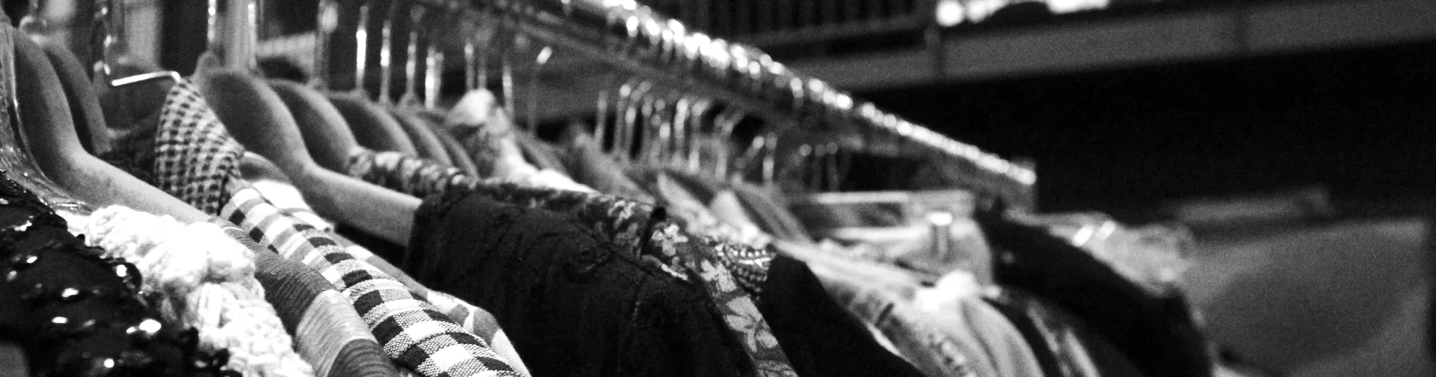 Black and white picture of clothes hanging on a rack.