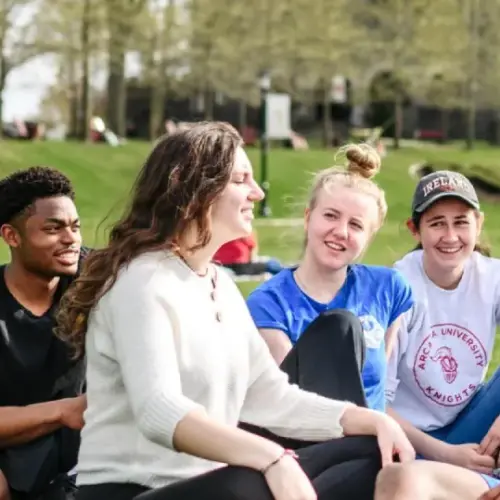 Nine students hang out on Arcadia's campus lawn