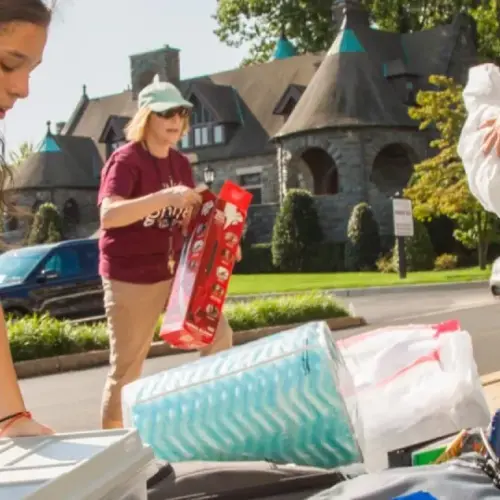 Students carrying items out of a car in front of Spruance Hall