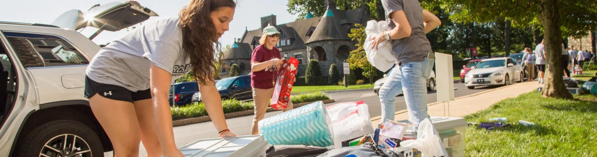 Students carrying items out of a car in front of Spruance Hall