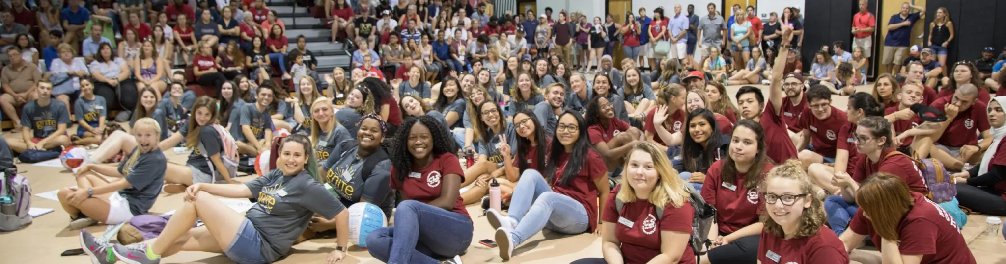 A very large group of students sitting in the gymnasium