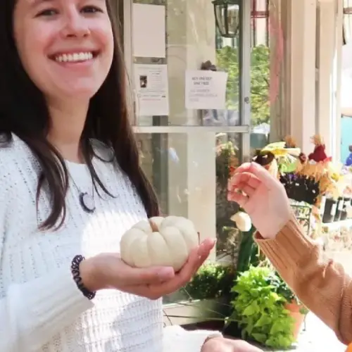 Students in a small town holding baby pumpkins in their hands