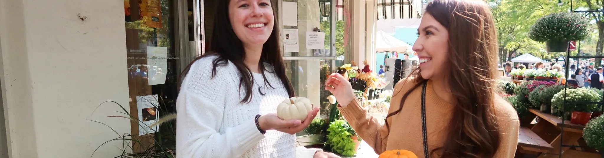 Students in a small town holding baby pumpkins in their hands