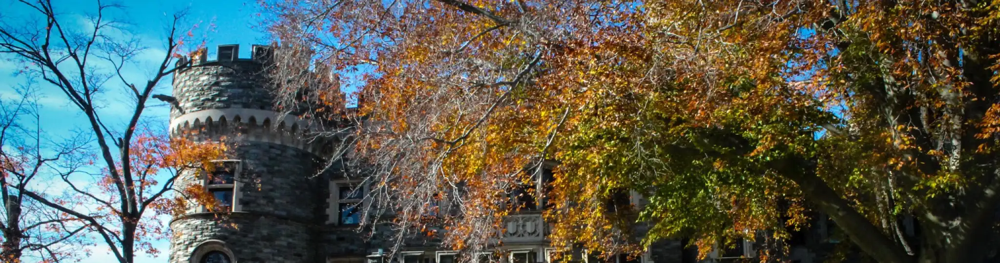 Photo of the top of Grey Towers Castle as the leaves of the trees around it are changing colors.