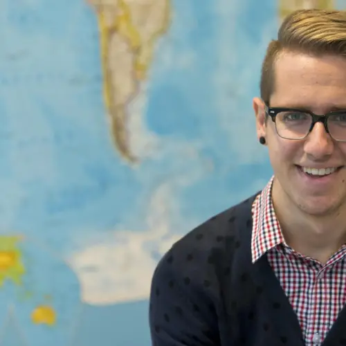 A student in a classroom in front of a map.