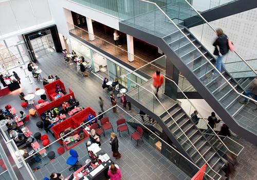 A view looking down from the inside of a tall building with several sets of stairs and glass walls