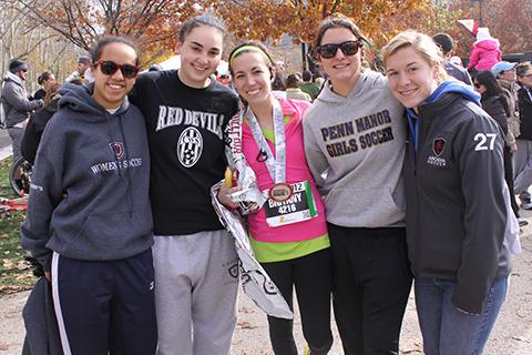 A student with a medal after running a race surrounded by friends