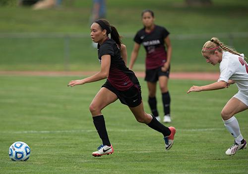 A women's soccer player chases after the ball