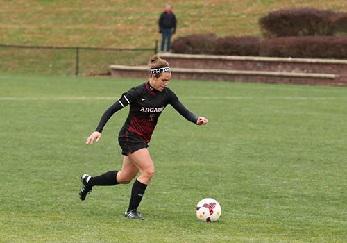 A woman soccer player about to kick the ball.