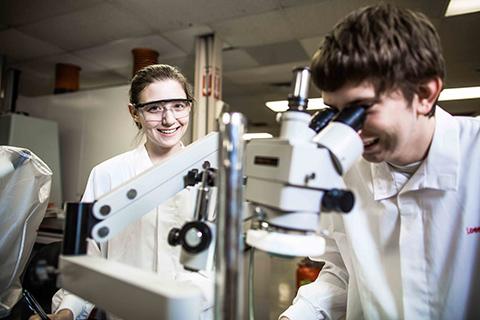 Two forensic science students using a microscope.