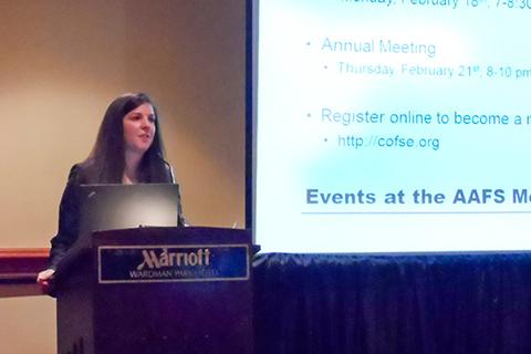 Heather Mazzanti standing at a podium with a presentation on a screen.