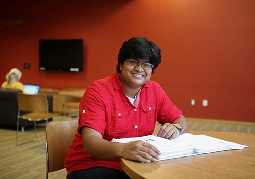 A student in the Fireplace Lounge smiling.