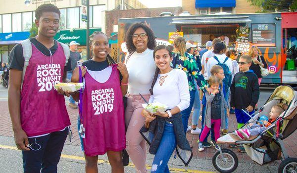 A large group standing in front of a food truck while wearing "Rock the Knight 2019" shirts.