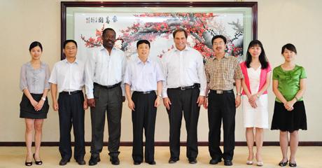 Eight people stand in a row in front of a large framed artwork depicting a cherry blossom tree