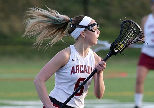 Arcadia lacrosse player running with her crosse raised.