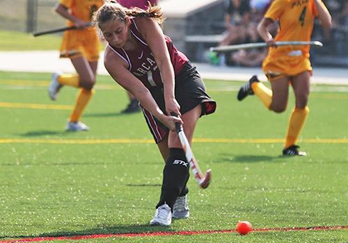 A field hockey player hitting the ball.