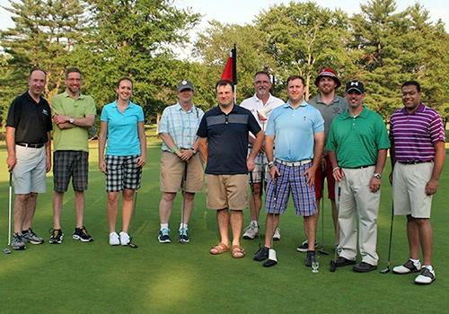 Arcadia golfers stand on a sunny golf course.