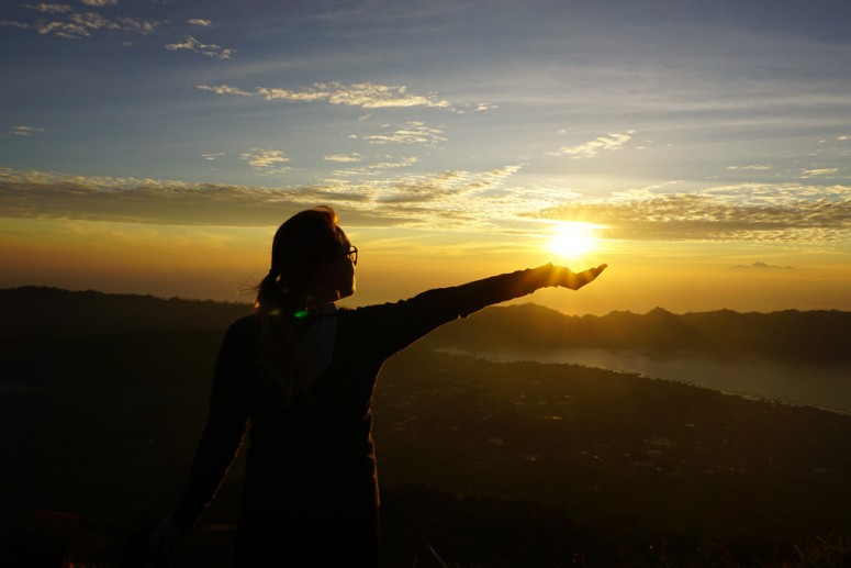 A student holds out her hand to make it look like she is holding the sun