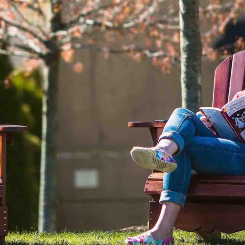 Woman reading book on Arcadia lawn chairs.