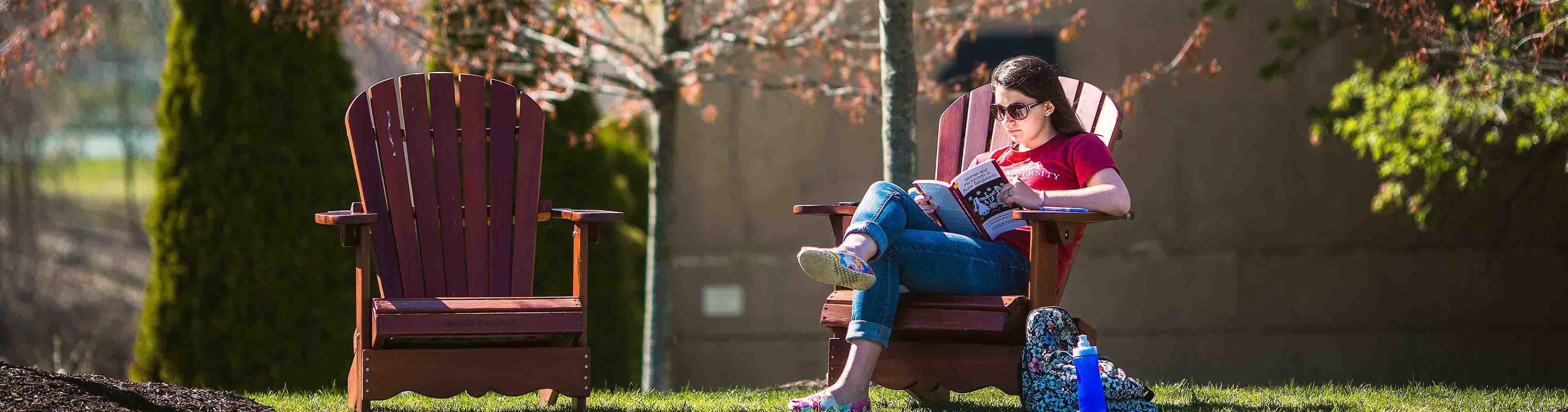 Woman reading book on Arcadia lawn chairs.