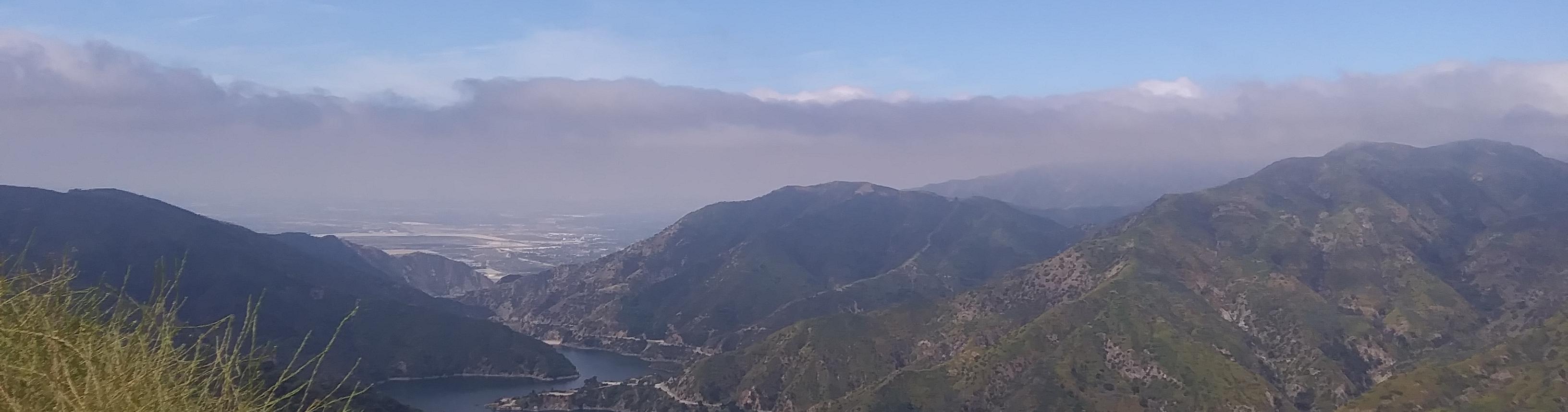 Landscape of mountains with a river running through, and flat land in the background.