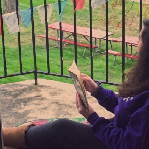 A person reading on a porch from their apartment.