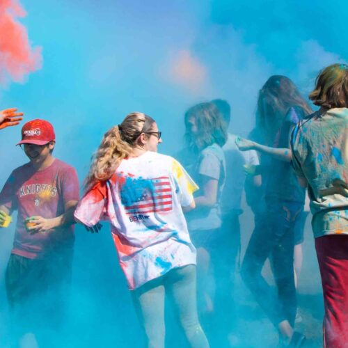 Several students throwing colored powder all over each other