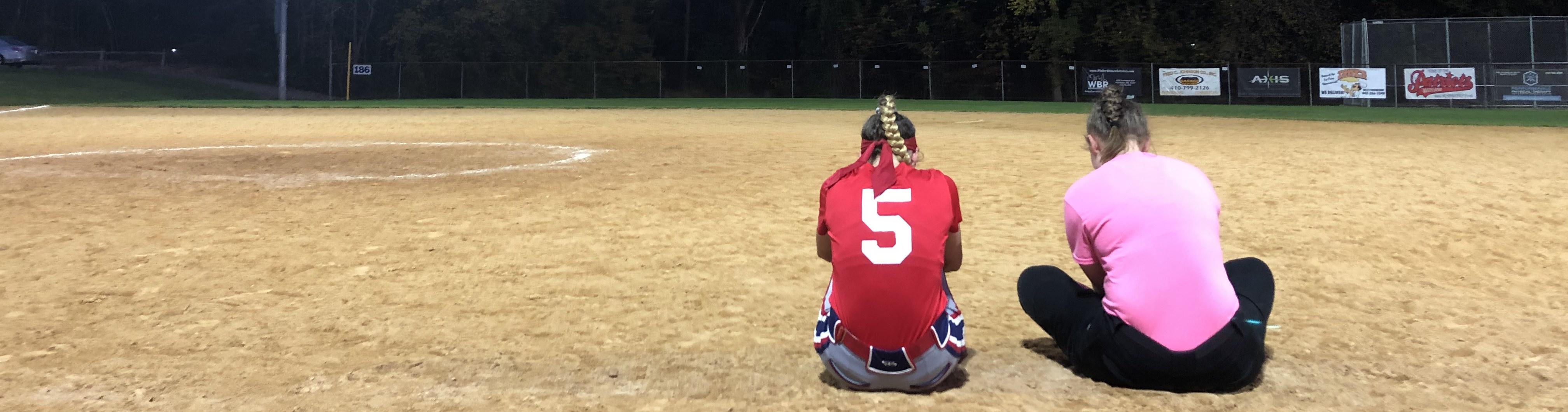 Two people sitting on baseball field