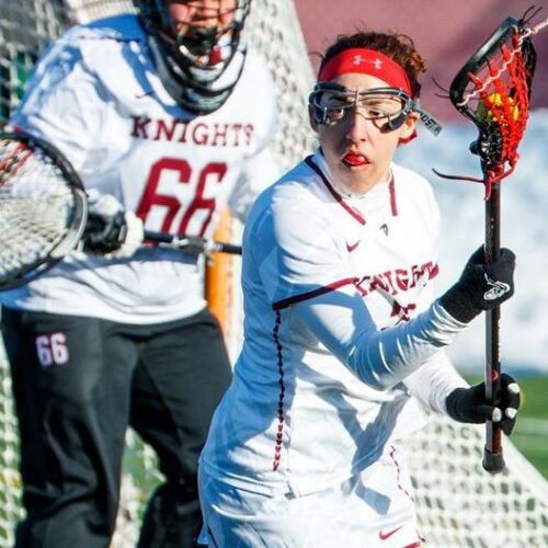 A lacrosse player for Arcadia controls the ball in front of the net vs Marywood