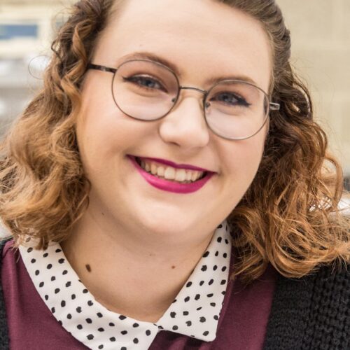 A young woman smiling in a science lab room.