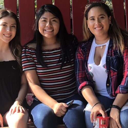 A group of students sitting together on a red wooden bench