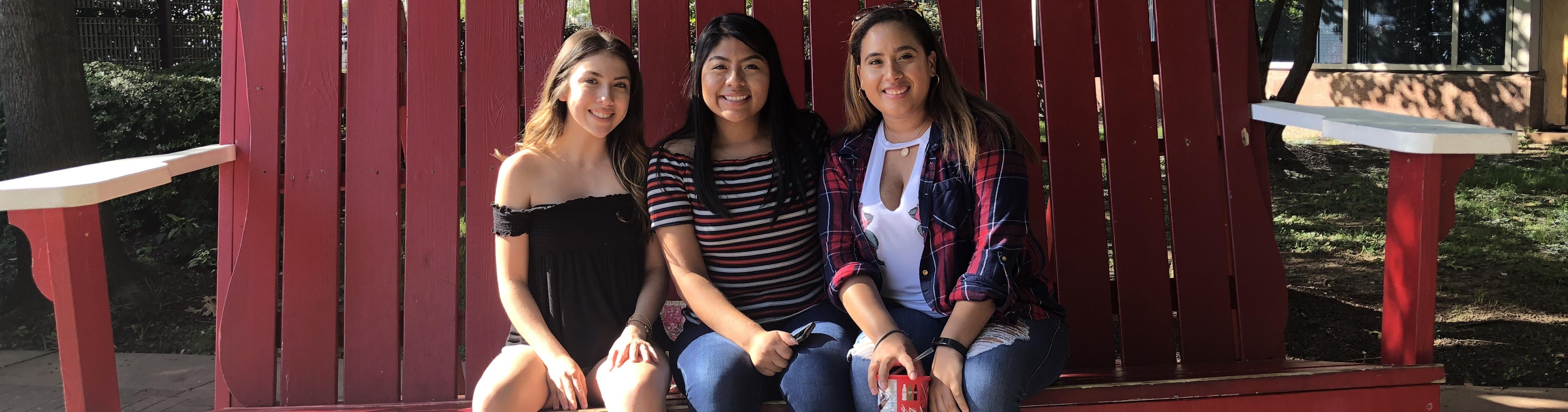 A group of students sitting together on a red wooden bench