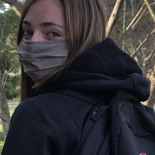 A student wearing a mask looks at the camera