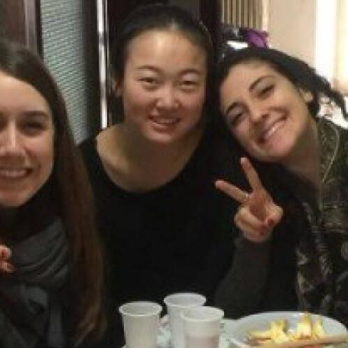 Six students smile at the camera holding up peace signs