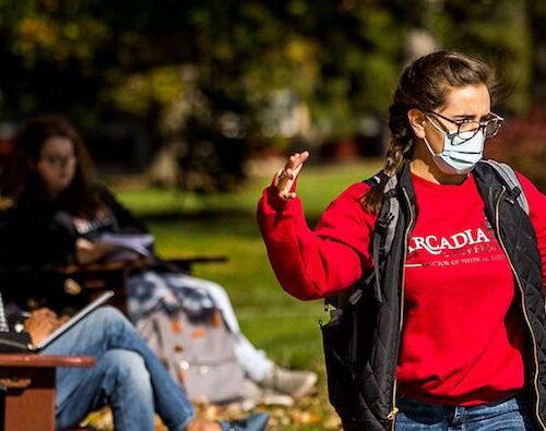 Two students wearing face masks talk to each other while walking on the Walk of Pride