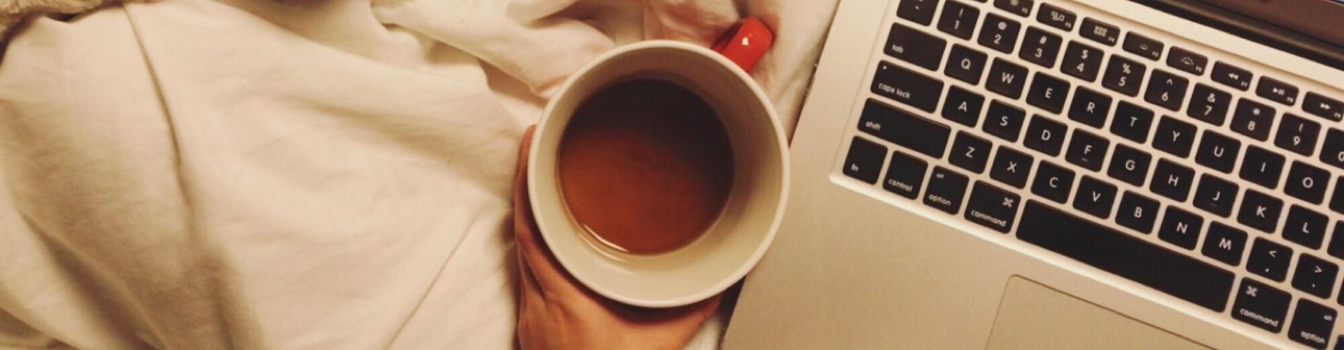 Aerial view of a cup of coffee and a laptop keyboard