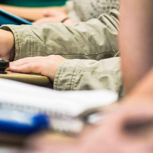 A photo of hands taking notes with a calculator on a desk