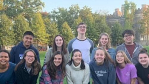 Two rows of students stand on Haber Green, the castle behind them