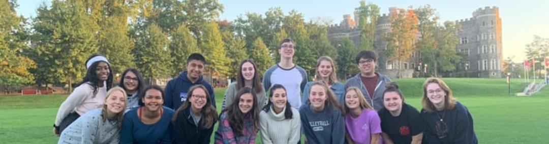 Two rows of students stand on Haber Green, the castle behind them