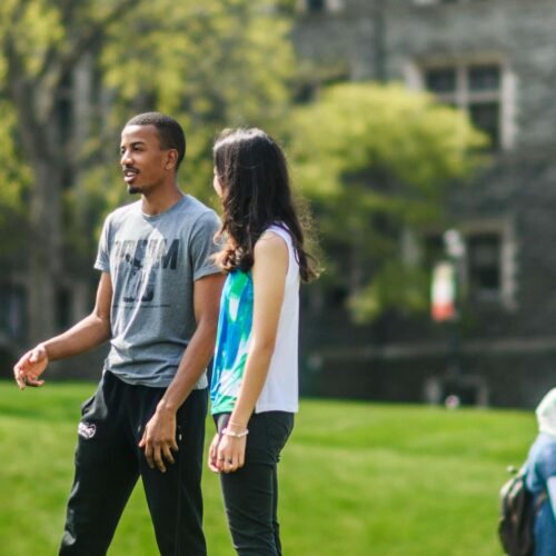 Two groups of people standing on Haber Green with Grey Towers Castle in the background