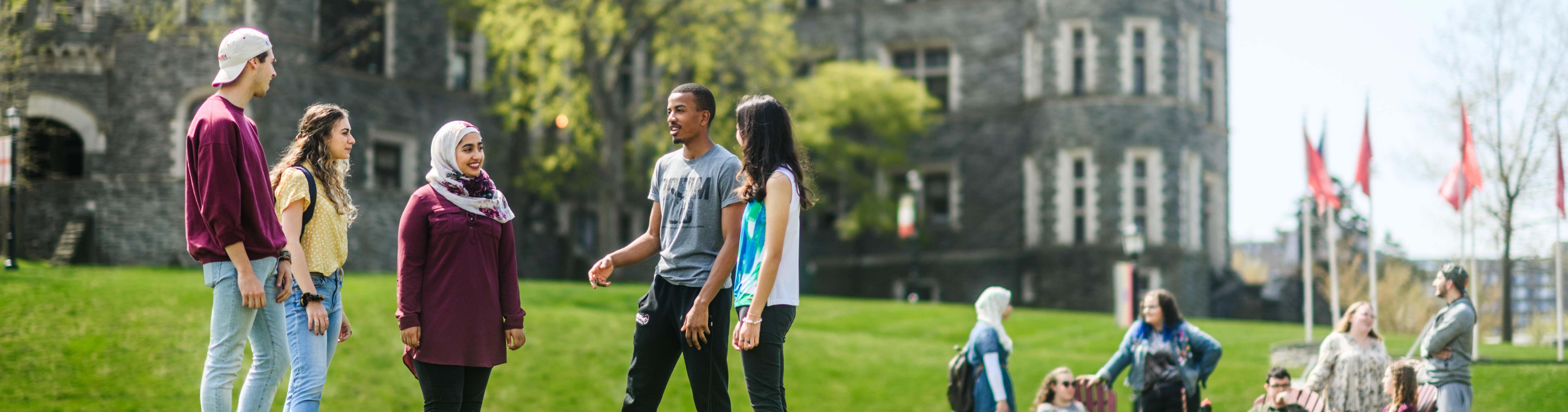 Two groups of people standing on Haber Green with Grey Towers Castle in the background