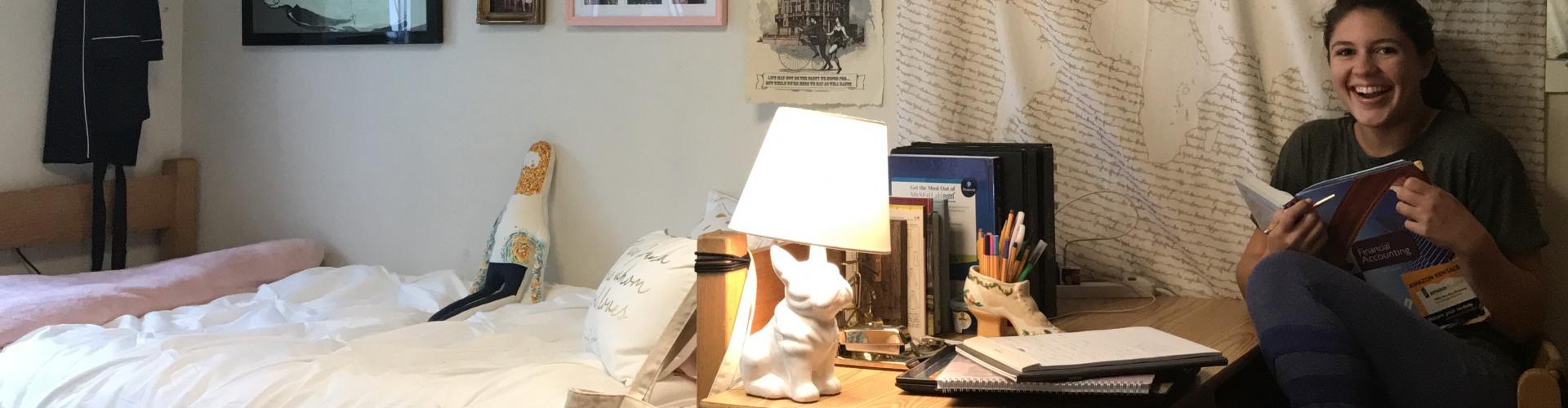 A very happy student reading while in her dorm