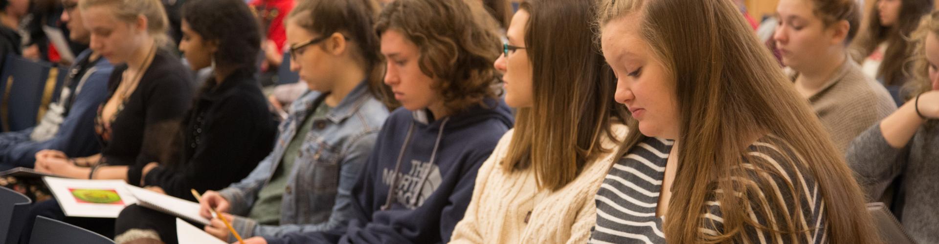 Students sitting and taking notes during a presentation.