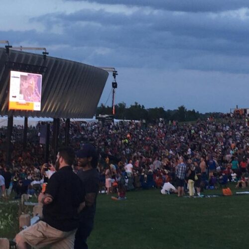 A large crowd at an outdoor concert in the evening