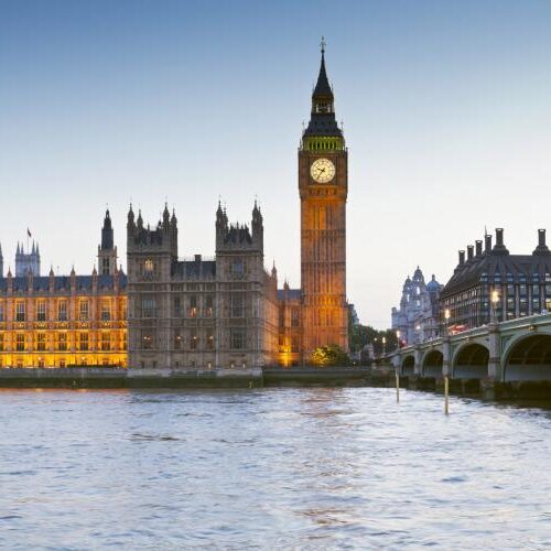 Parliament building in London, lit and seeming to glow in the evening along the Thames