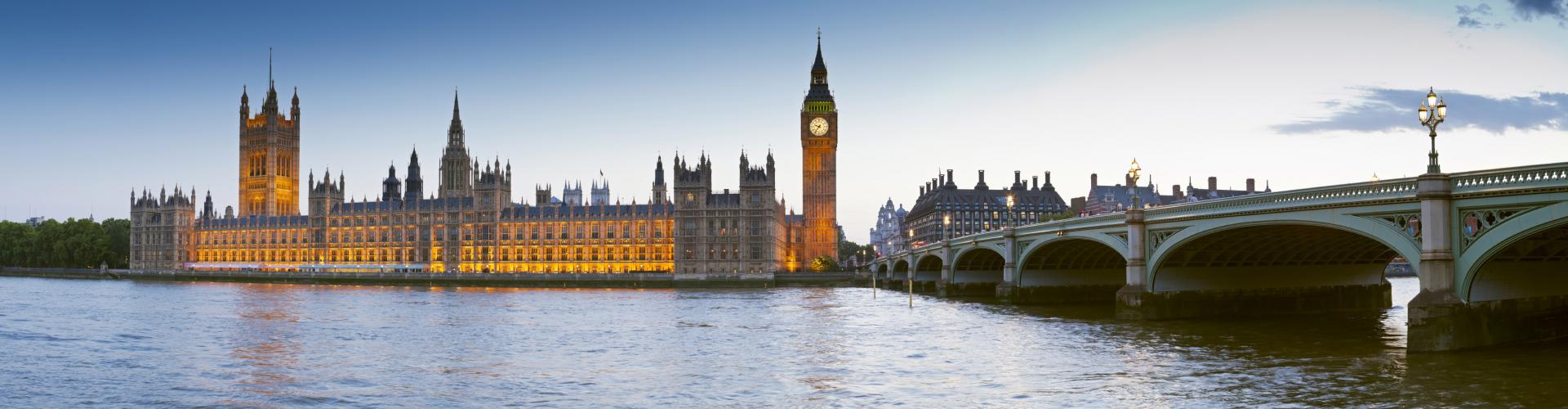 Parliament building in London, lit and seeming to glow in the evening along the Thames