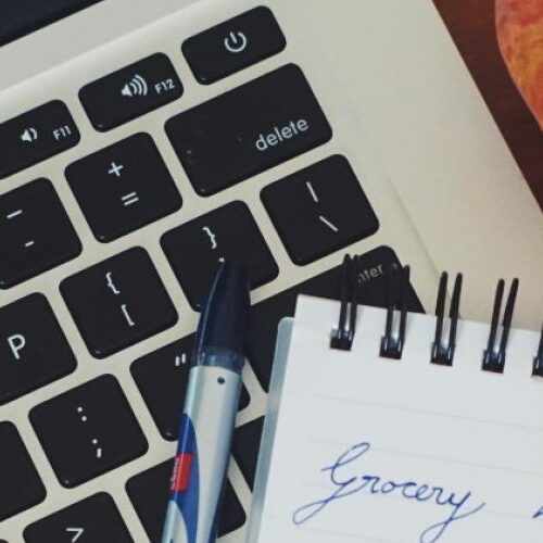 Closeup of MacBook Air and a grocery list.