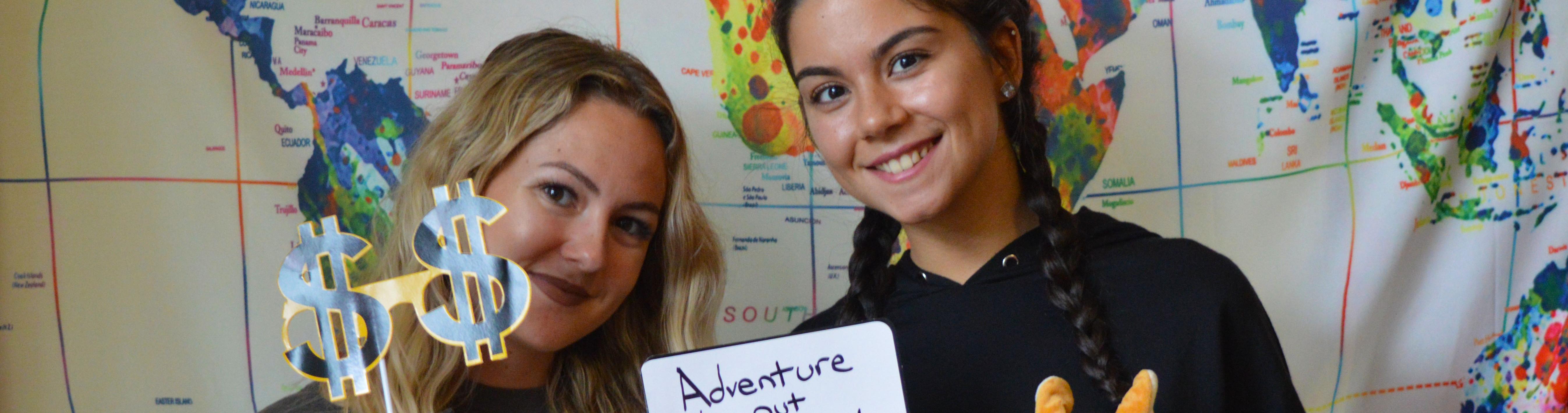 Two students stand in front of a world map