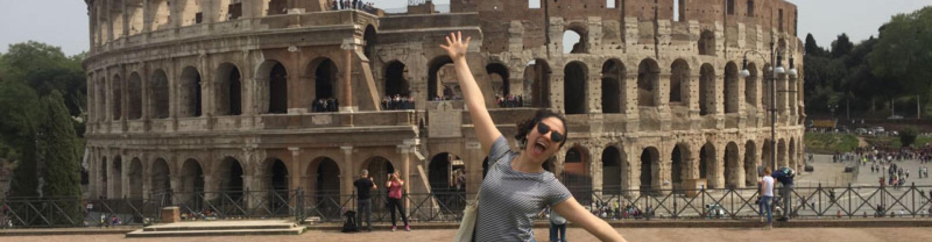 A very happy woman standing in front of the Colosseum