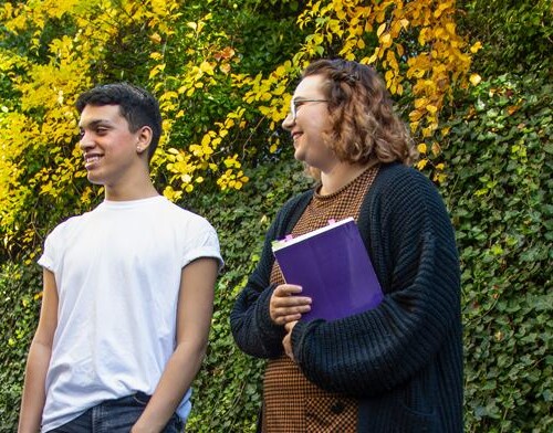 Photo of four students standing outside Easton Hall talking and laughing.